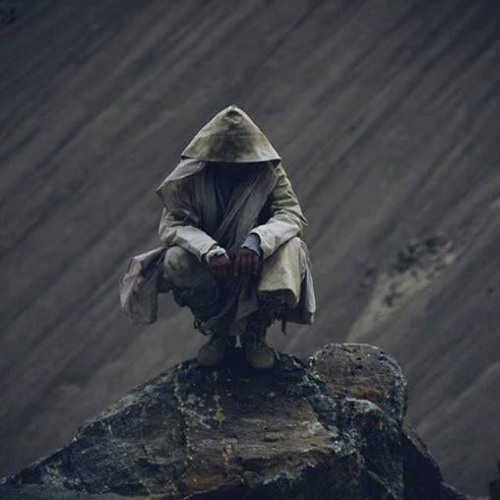 crouched hooded figure in a long coat sitting on the edge of a rock high above a fast streaming river. the whole picture is dark.